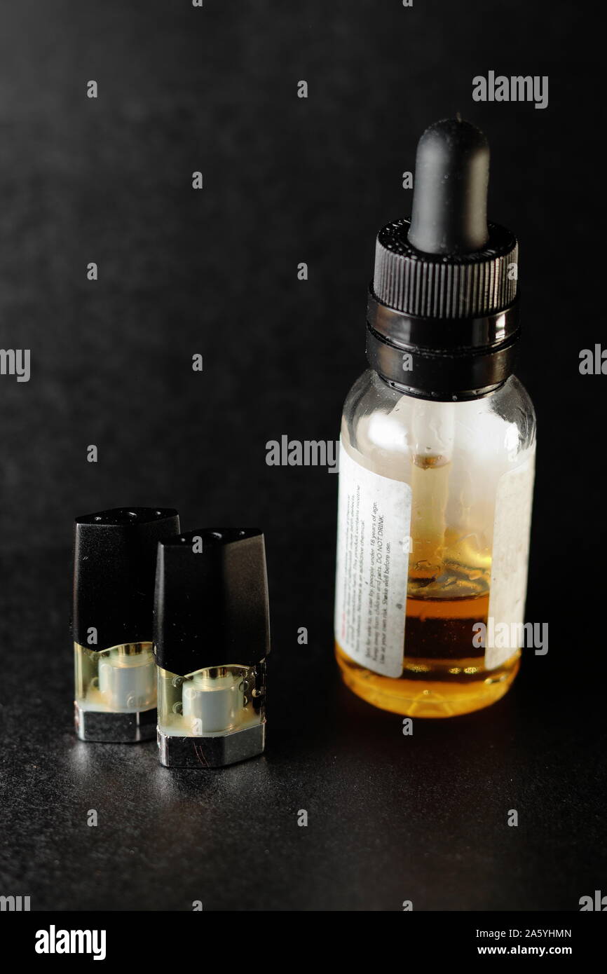 E-Saft vape nachfüllen Pods mit mit einer Flasche orange e-liquid, isoliert in der Nähe bis schwarzen Hintergrund Stockfoto