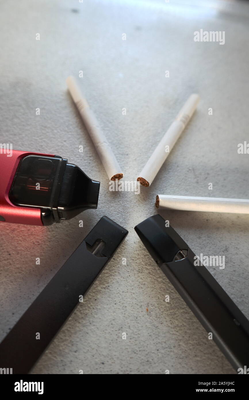 3 vape Elektronische Zigarette Geräte und 3 Zigaretten in einem sternförmigen Muster auf weißem strukturierten Hintergrund Nahaufnahme Stockfoto