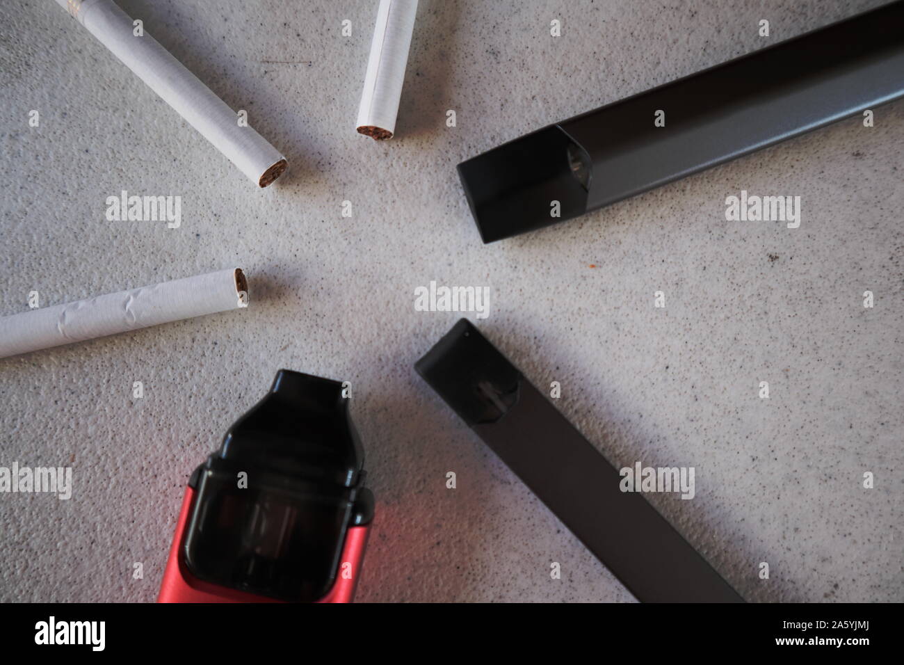 3 vape Elektronische Zigarette Geräte und 3 Zigaretten in einem sternförmigen Muster auf weißem strukturierten Hintergrund Nahaufnahme Stockfoto