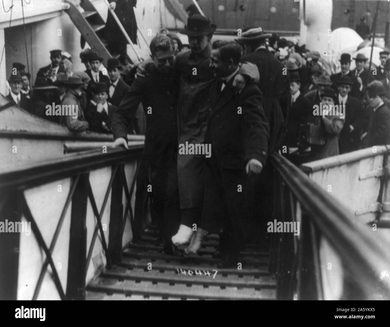 Verlust der Olympic White Star Line-Klasse Schiff RMS Titanic mit einem Eisberg am 12. April 1912 ihre Jungfernfahrt angeschlagen. Überlebende Funker Harold Bride, Füße bandagiert, durchgeführt, Gangway, New York. Disaster Stockfoto