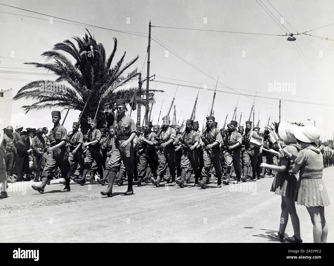 Foto von zwei Kindern, winken, als französische Truppen entlang Avenue Gambetta, während der Sieg der Alliierten Parade, Tunis, Tunesien marschieren. Datiert 1943 Stockfoto