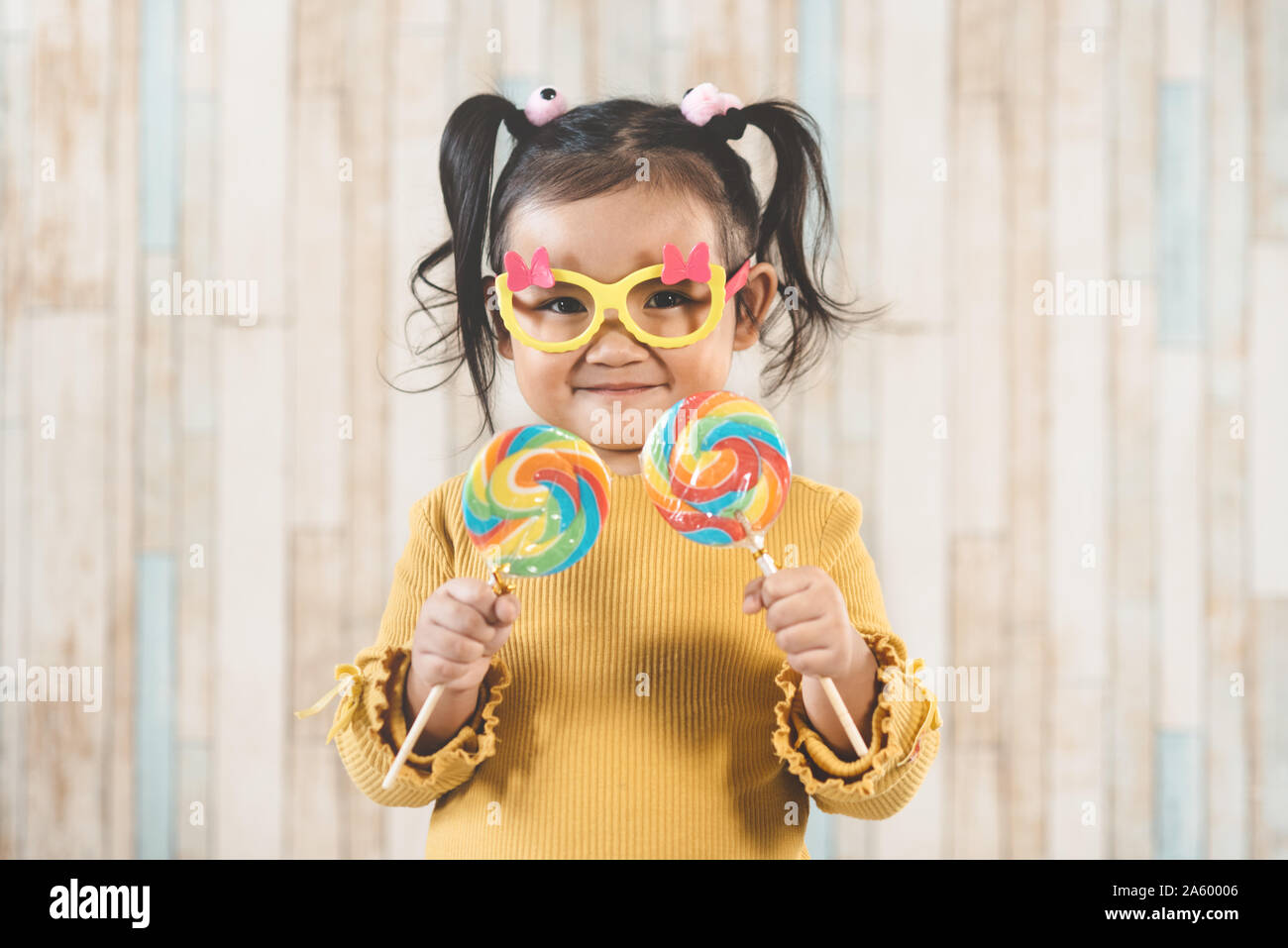 Süße kleine asiatische Mädchen halten und essen eine bunte Lollipop. Konzept der Mundpflege und Süßigkeiten Tag Stockfoto