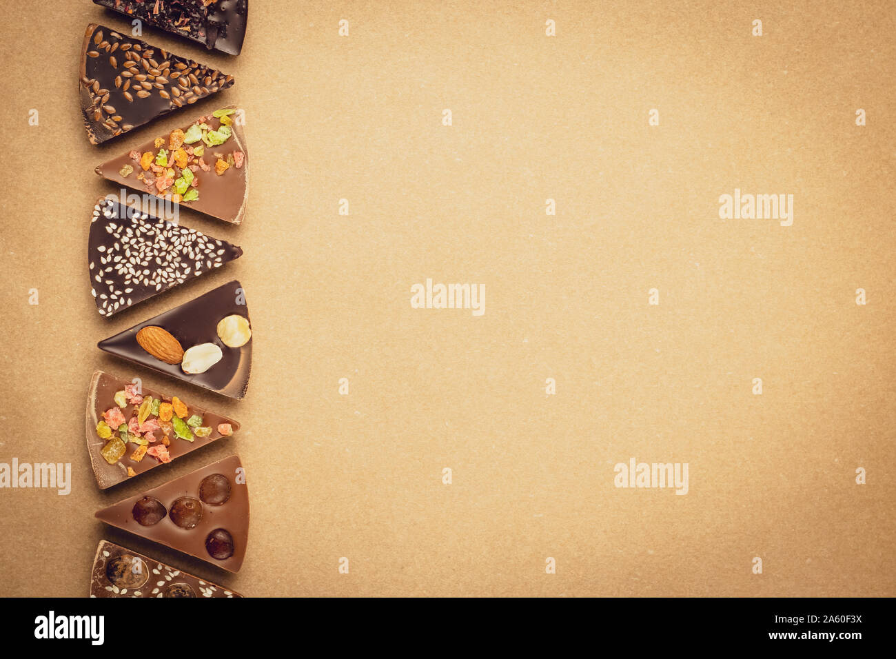 Stücke Schokolade für das Handwerk. Süße Nachspeise. Gewürzter Schokoladen auf vintage Pergament, braunen Hintergrund. Kopieren Sie Platz. Rahmen mit Text. Kunst Stockfoto