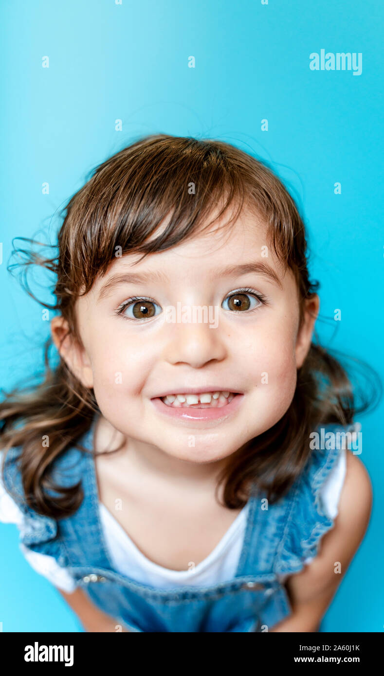 Portrait von niedlichen kleinen Mädchen lächelnd sehr ausdrucksstark auf blauem Hintergrund Stockfoto