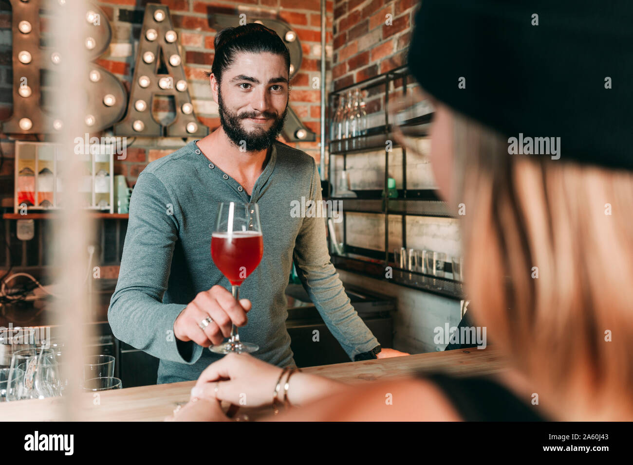 Barkeeper serviert Frau einen Cocktail Stockfoto