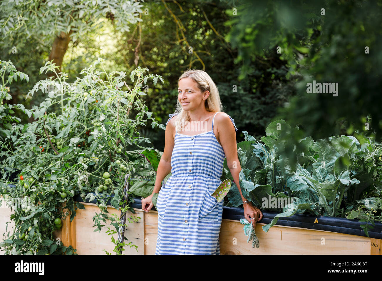 Blonde Frau, der vor ihr steht angehoben Bett in Ihrem eigenen Garten Stockfoto