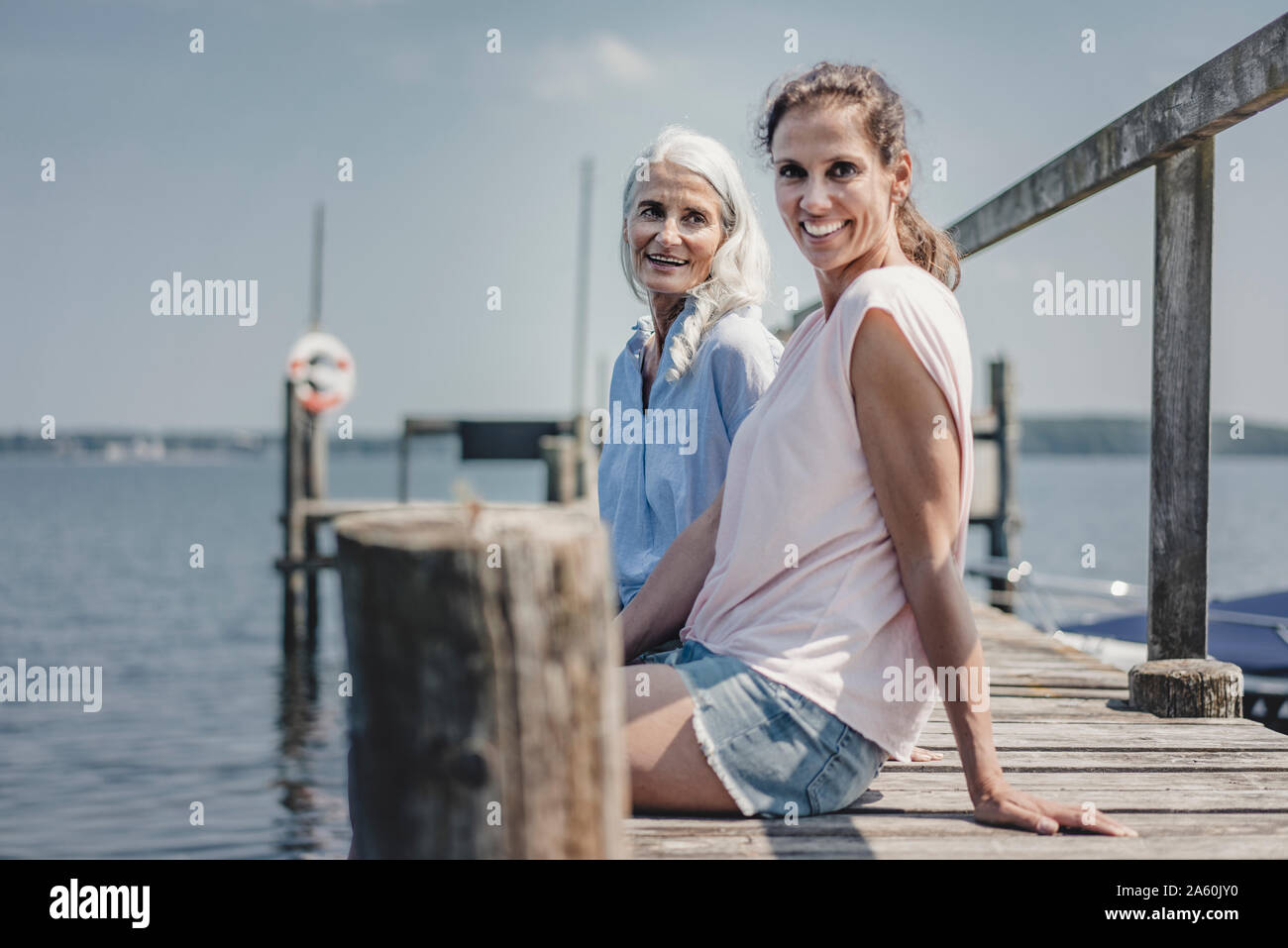 Mutter und Tochter sitzen am Bootsanleger, Entspannen am Meer Stockfoto