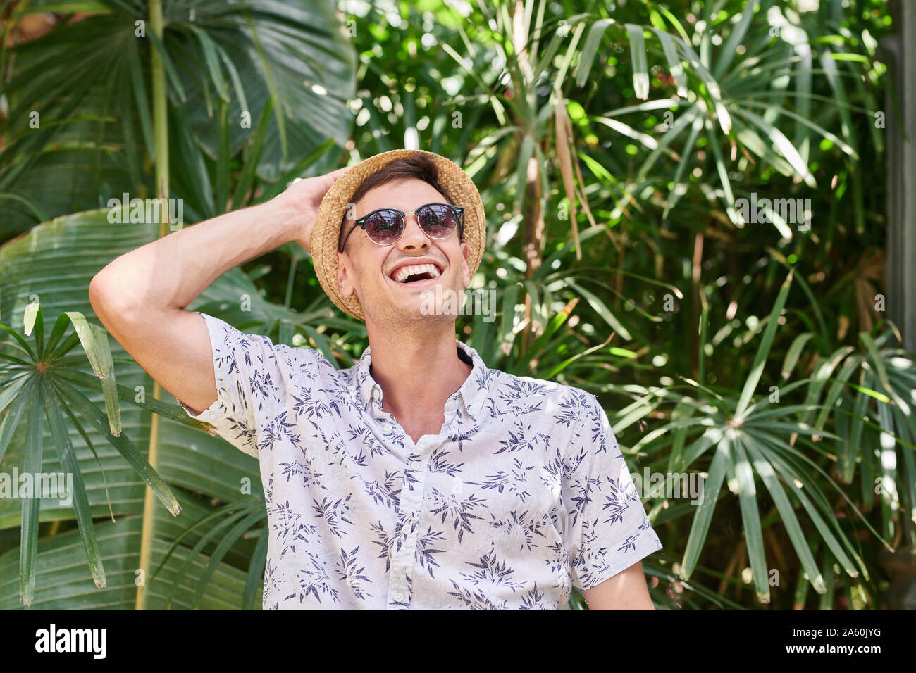 Lächelnder Mann mit Hut und Sonnenbrille in einem Park Stockfoto