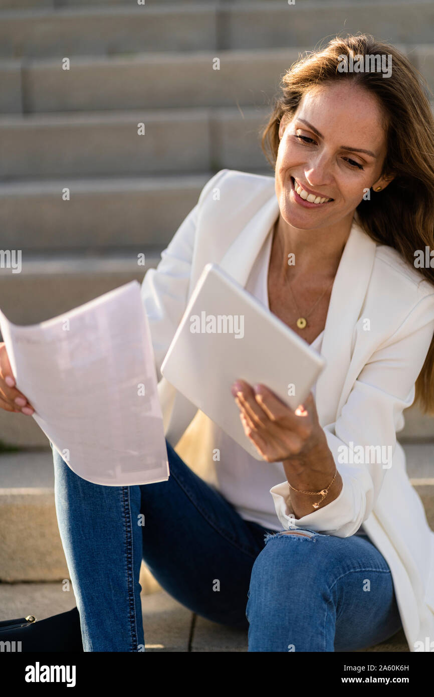 Geschäftsfrau, sitzen auf der Treppe mit Papier und Tablet Stockfoto