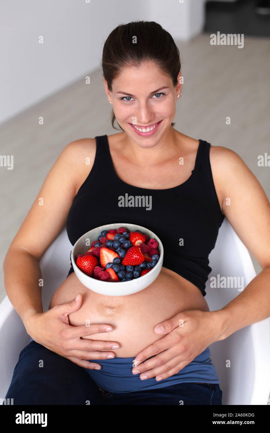 Junge schwangere Frau ist Essen verschiedene Arten von frischem Obst Stockfoto