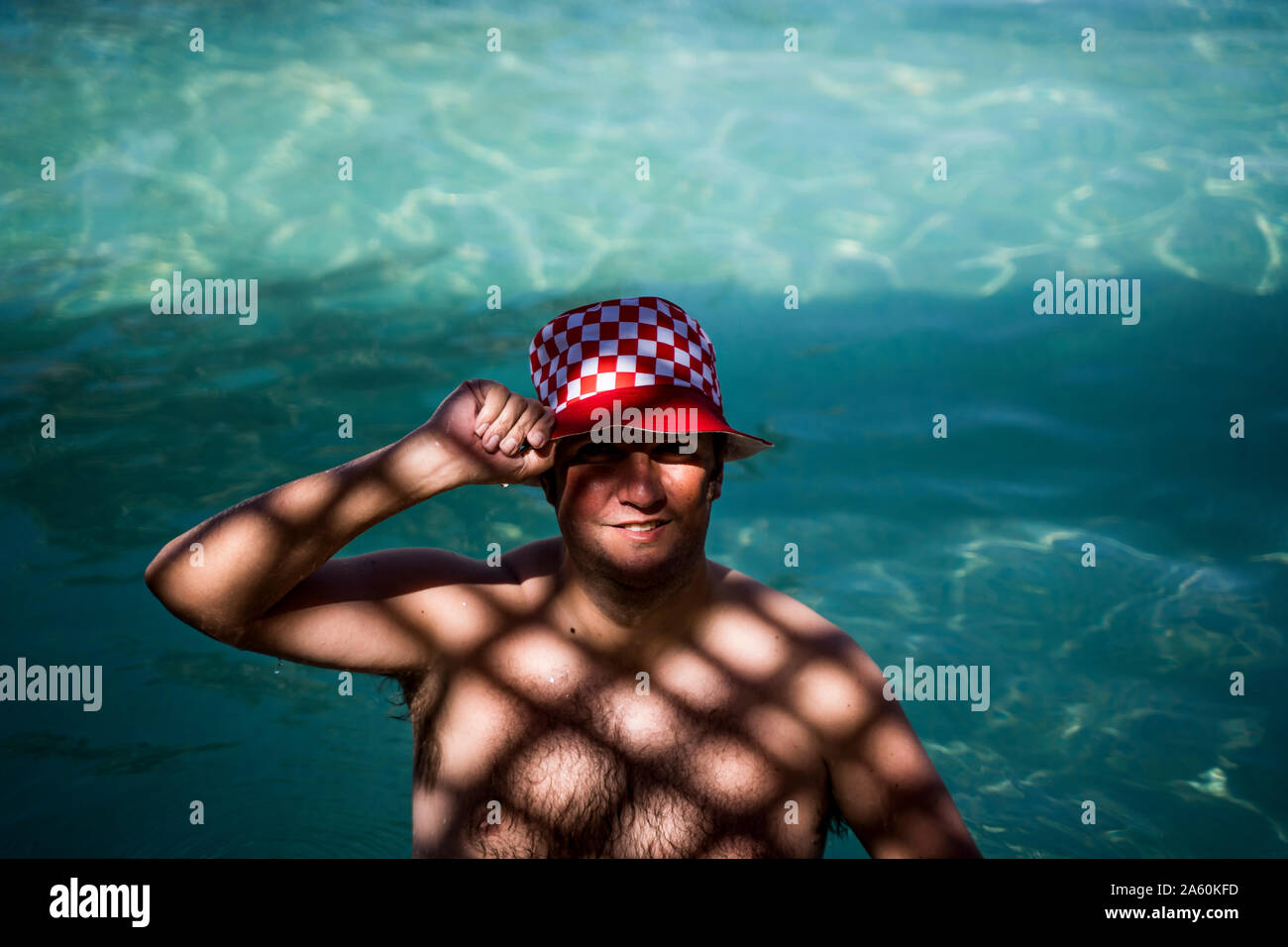 Portrait von übergewichtigen Mann mit Hut im Pool in schattigen Bereich Stockfoto