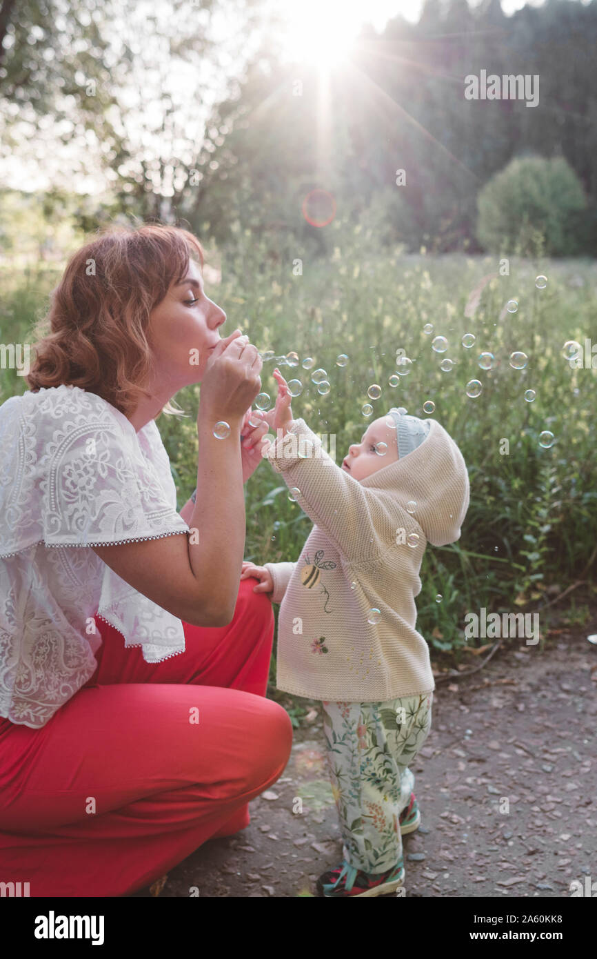 Mutter macht Seifenblasen für ihre kleine Tochter Stockfoto