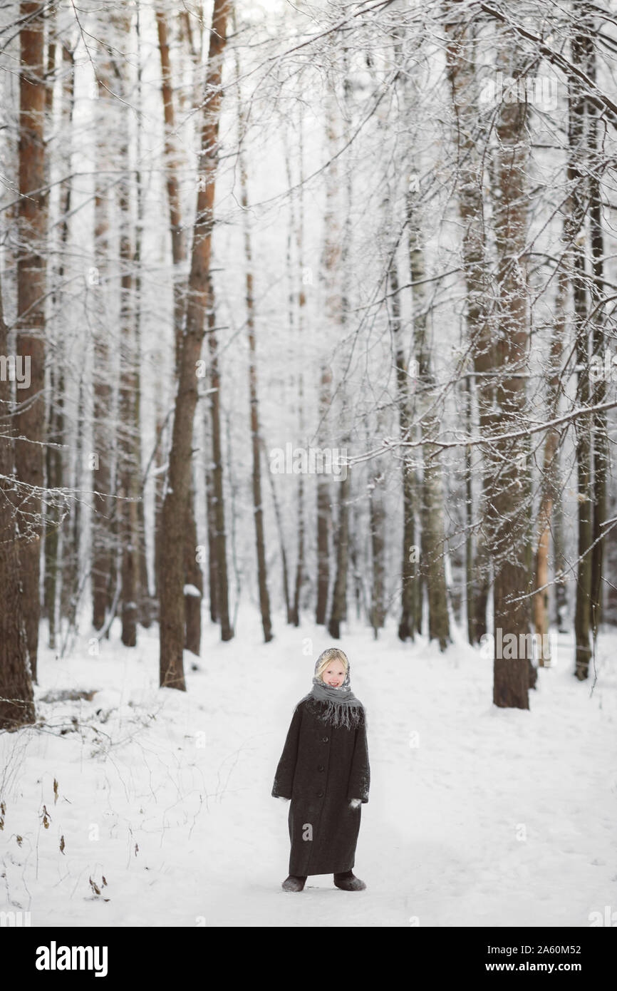 Lächelnd kleine Mädchen stand vor der Winter Forest Stockfoto