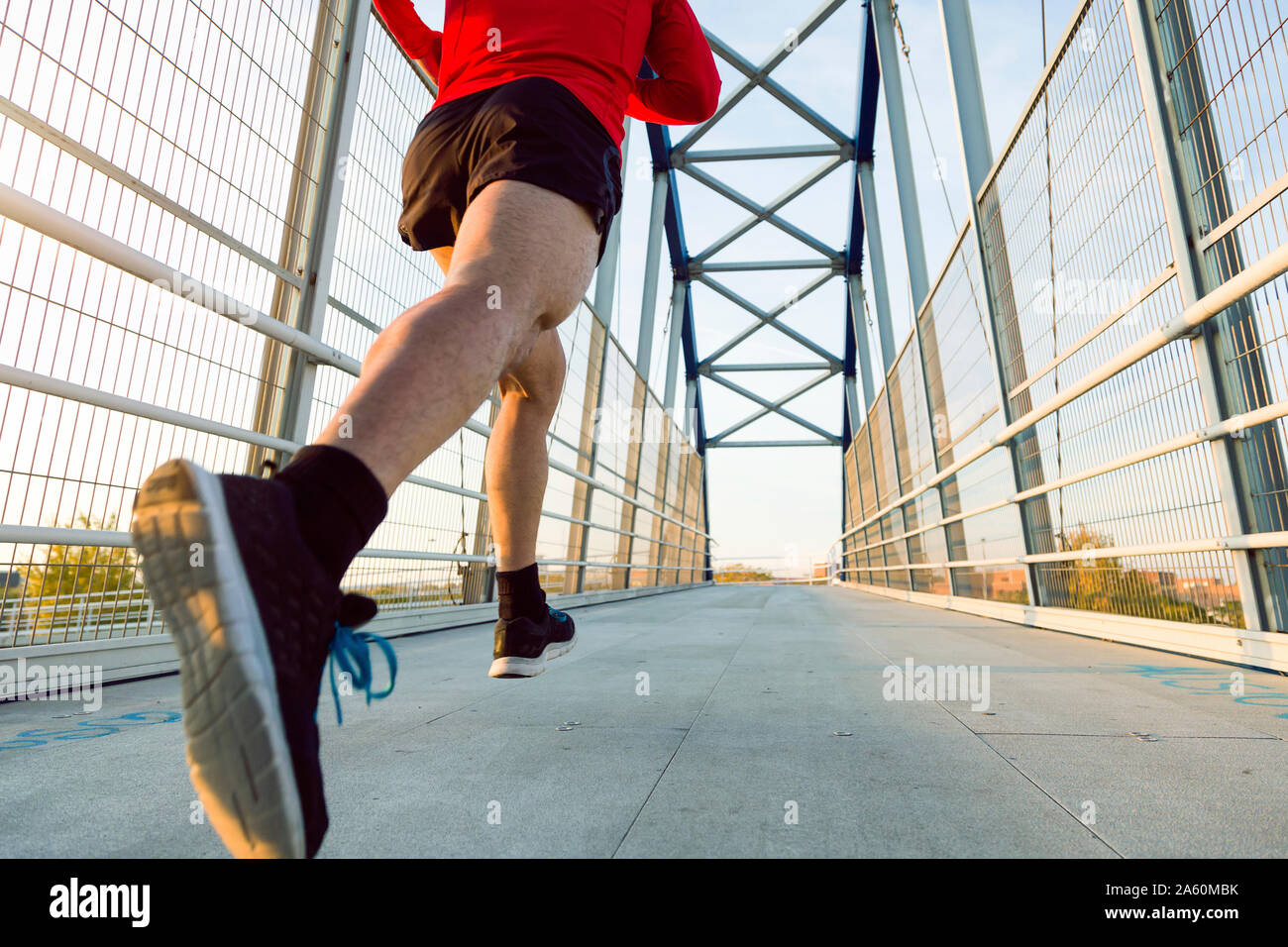 Jogger mit Smartphone im Arm pocket läuft auf einer Brücke Stockfoto