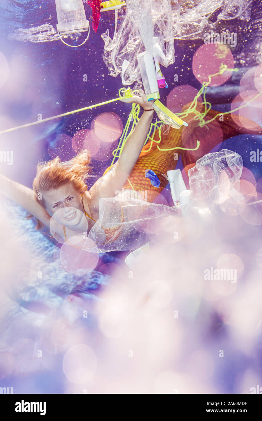 Traurige Teenager Meerjungfrau Girl von Kunststoffabfällen umgeben unter Wasser Stockfoto