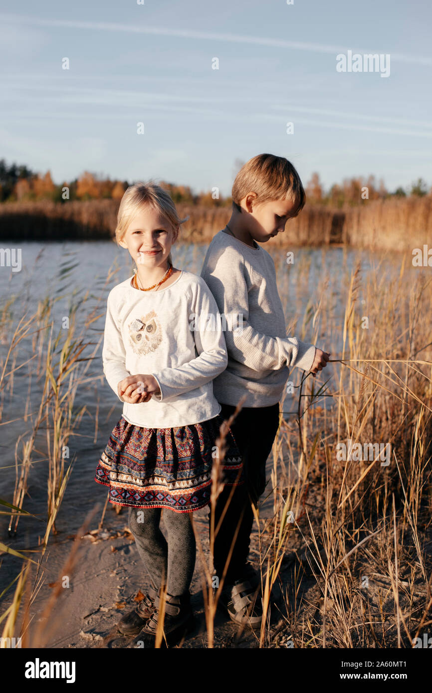 Geschwister stehen am Flußufer im Herbst Stockfoto