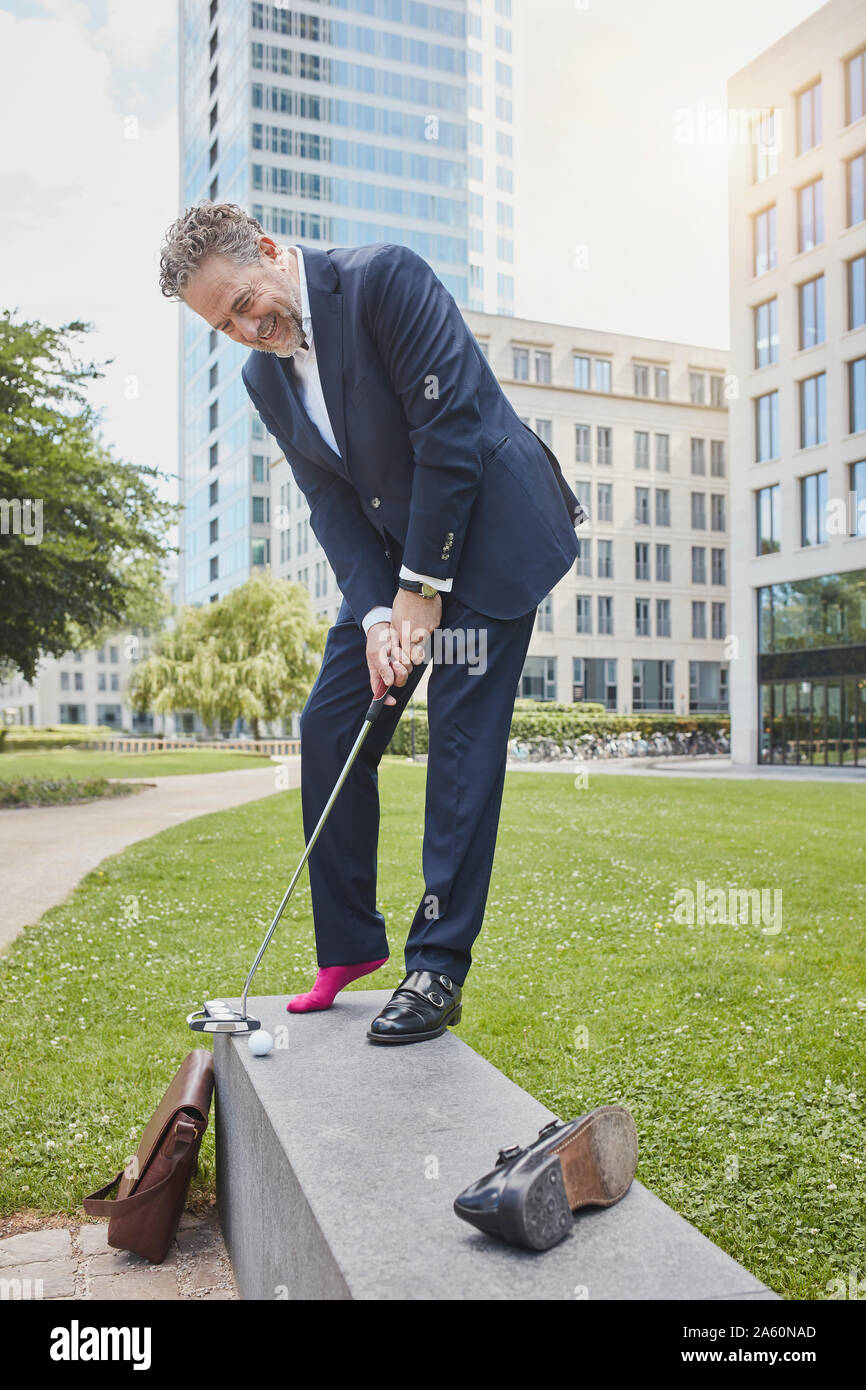 Reifen Geschäftsmann Golf spielen in der Stadt Stockfoto