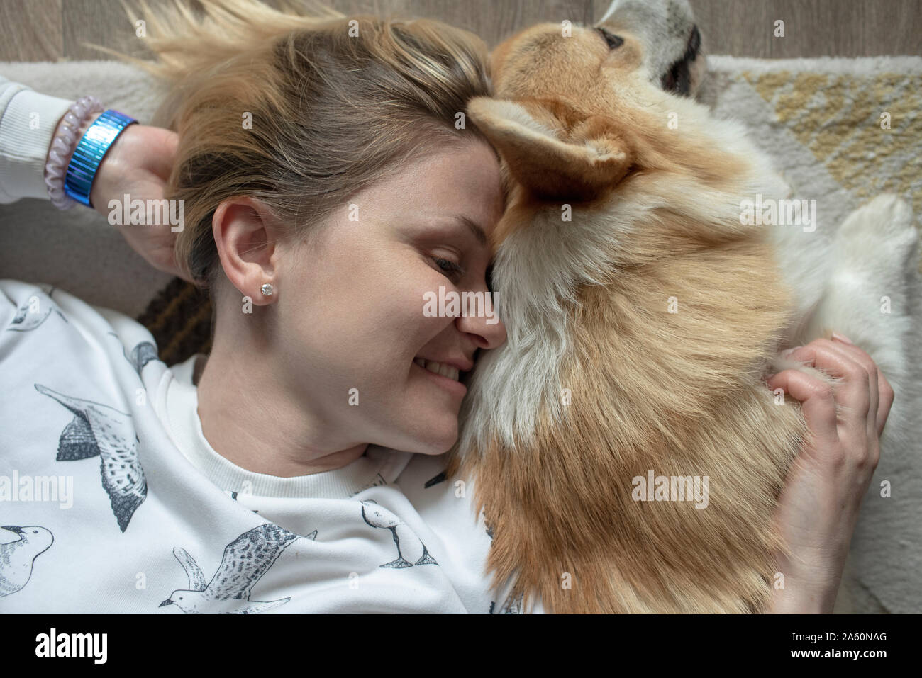 Glückliche Frau liegen auf dem Florr zu Hause Kuscheln mit Ihrem Hund Stockfoto
