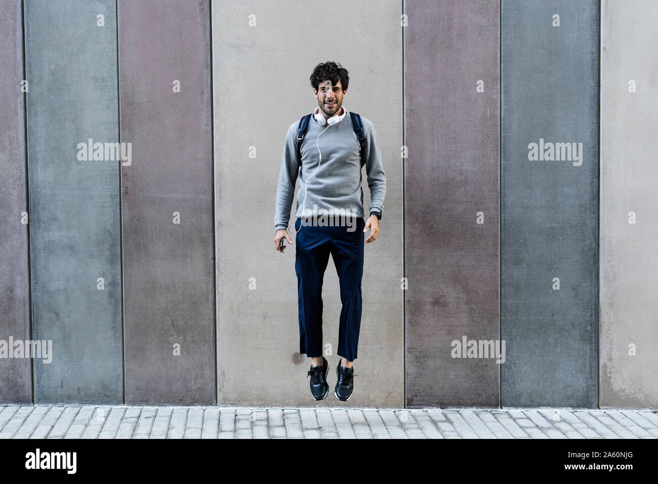 Mann mit Handy vor einer Wand springen Stockfoto