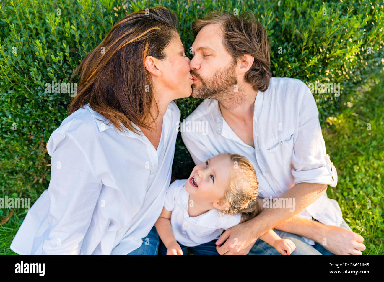 Eltern Küssen mit kleinen Tochter beobachten Stockfoto
