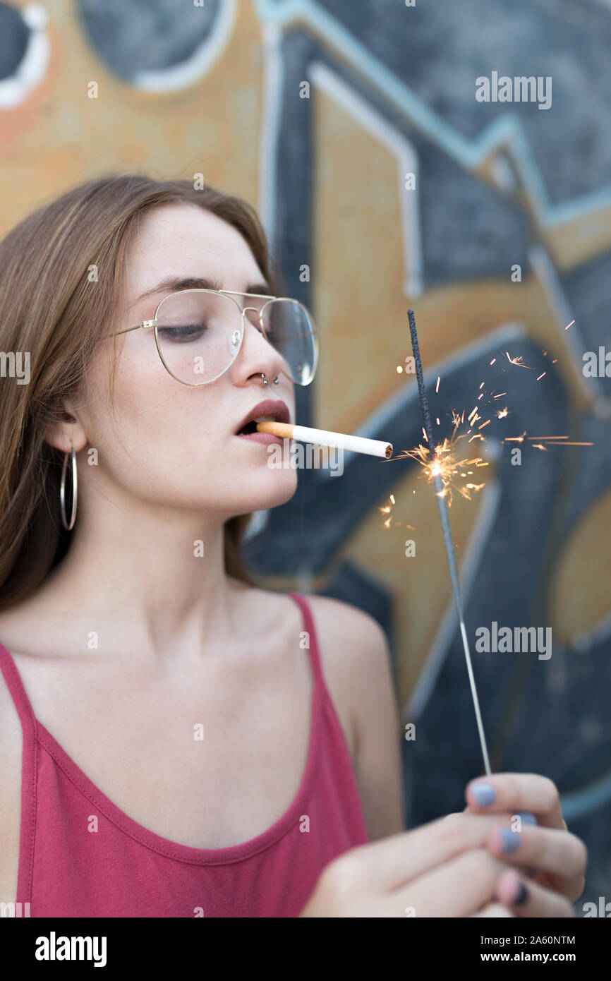 Junge Frau Beleuchtung Zigarettenanzünder mit einer Wunderkerze Stockfoto