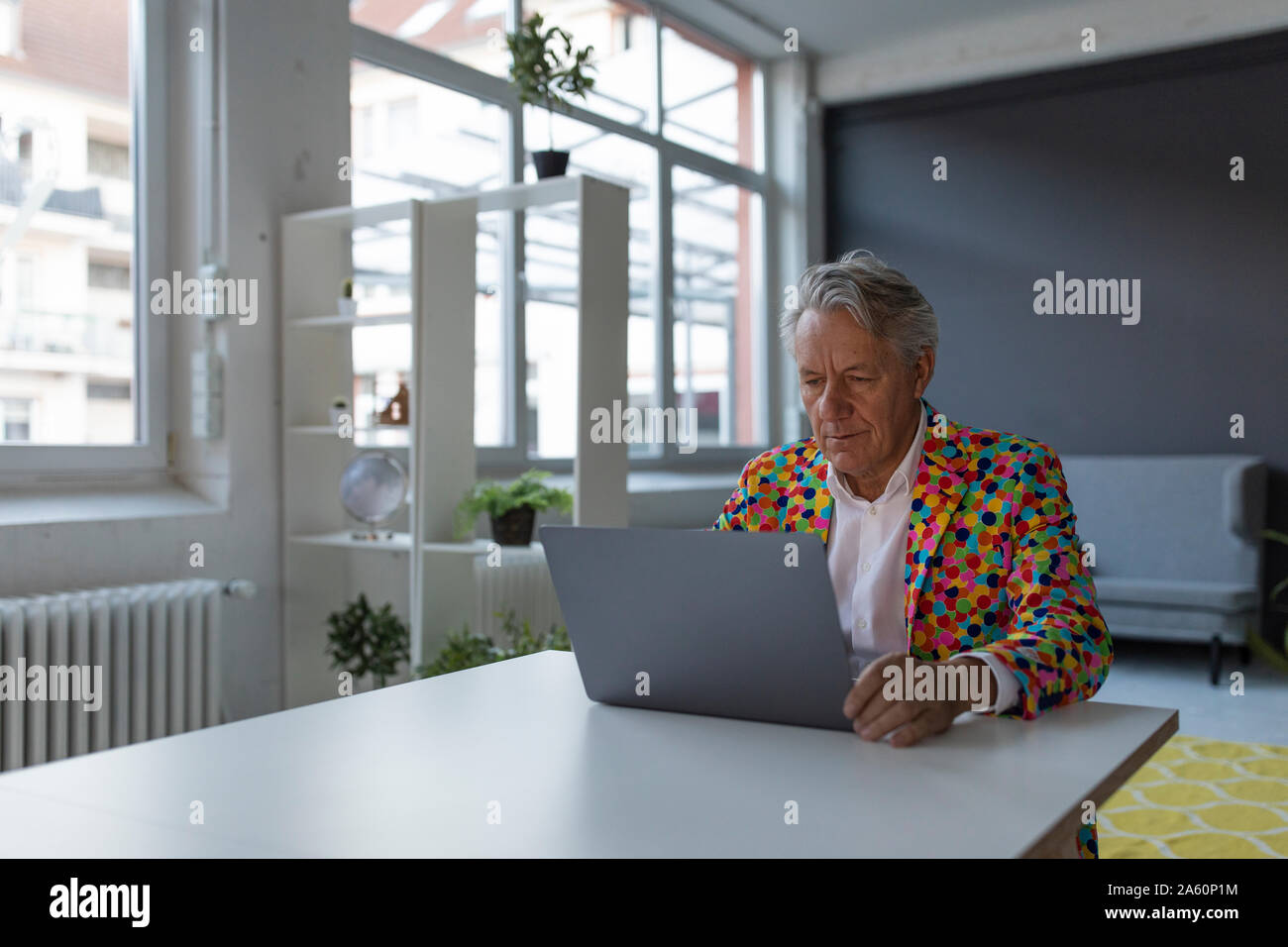Ältere Unternehmer tragen bunte Sport Jacke mit Laptop Stockfoto