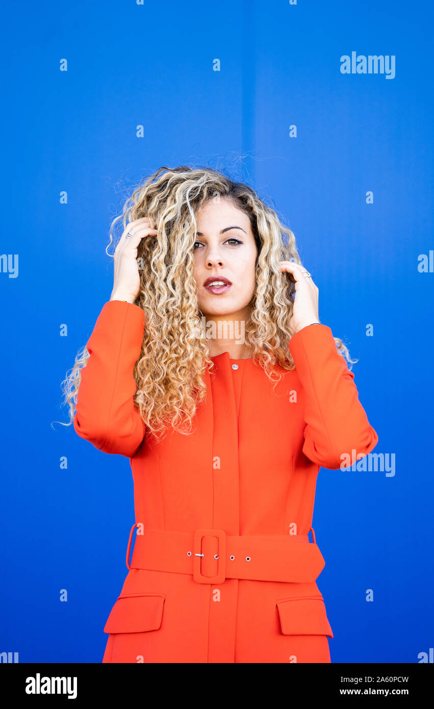 Porträt der jungen Frau das Tragen der roten Kleid vor blauem Hintergrund Stockfoto