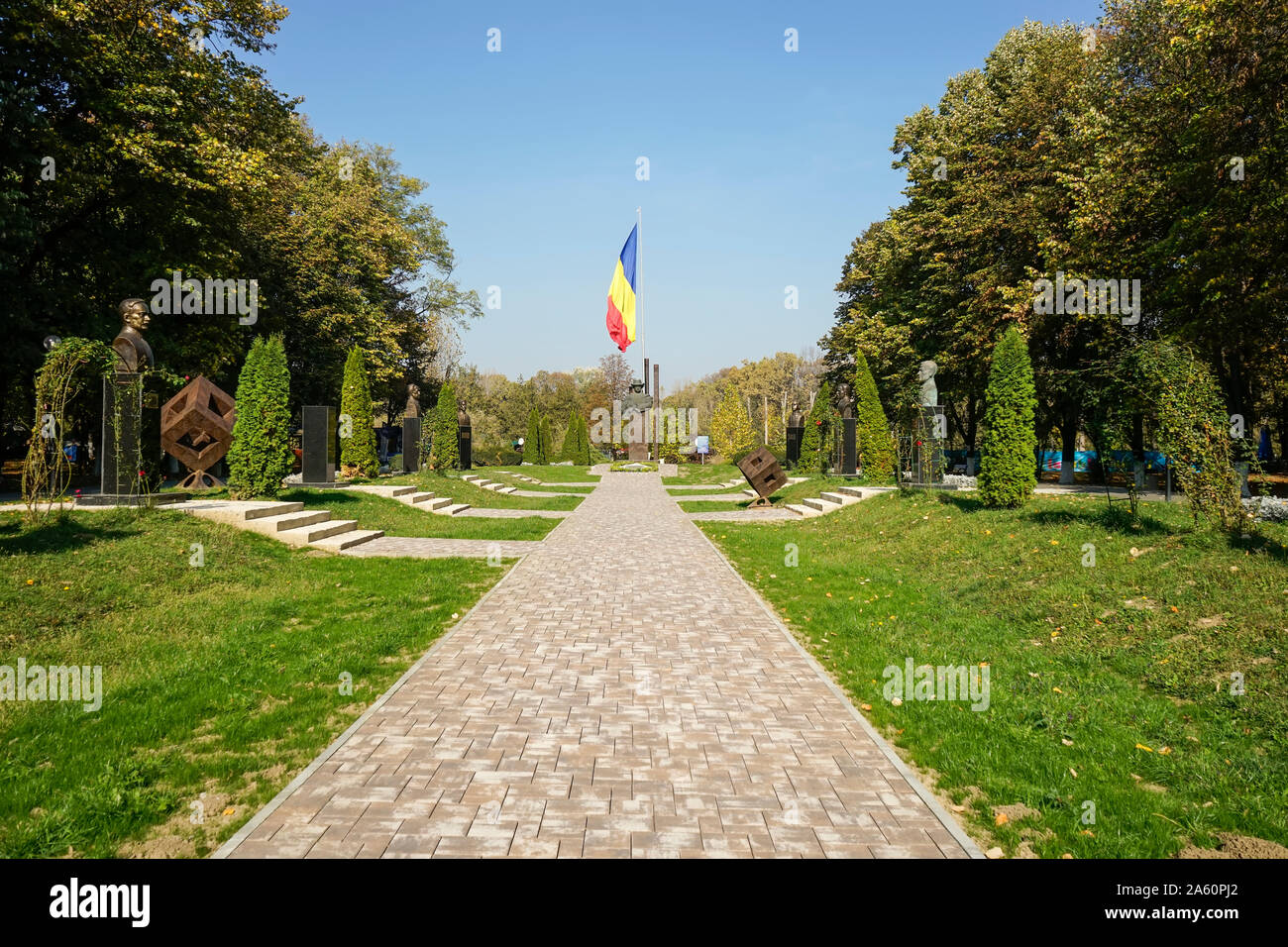 Gasse, die mit den Statuen der rumänischen Literatur Persönlichkeiten und der rumänischen Flagge im Hintergrund an Constantin Stere Park, Ploiesti Stockfoto