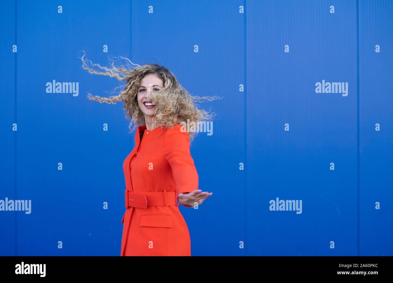 Portrait von glücklichen jungen Frau das Tragen der roten Kleid vor blauem Hintergrund Stockfoto
