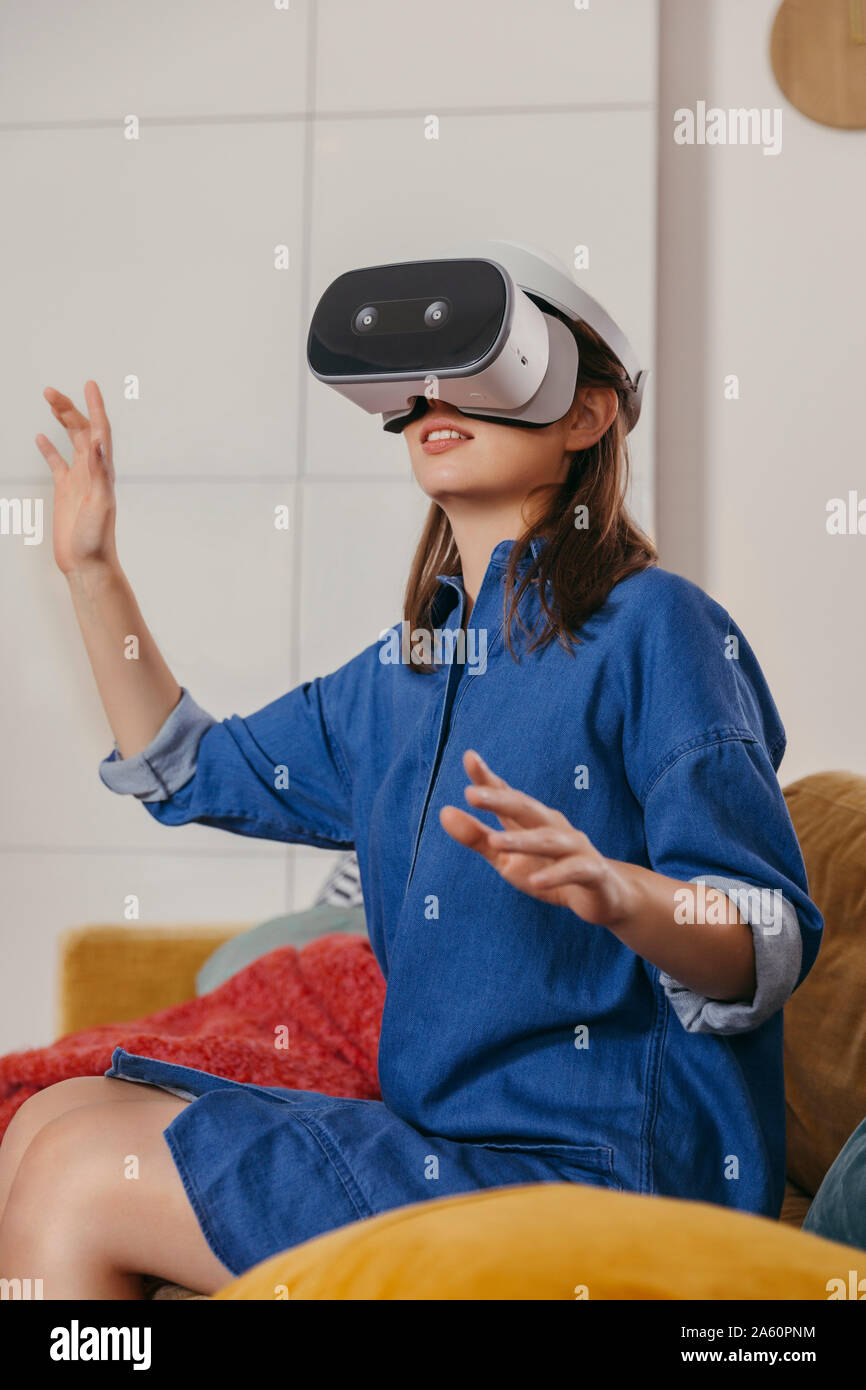 Junge Frau mit VR-Brille zu Hause Stockfoto