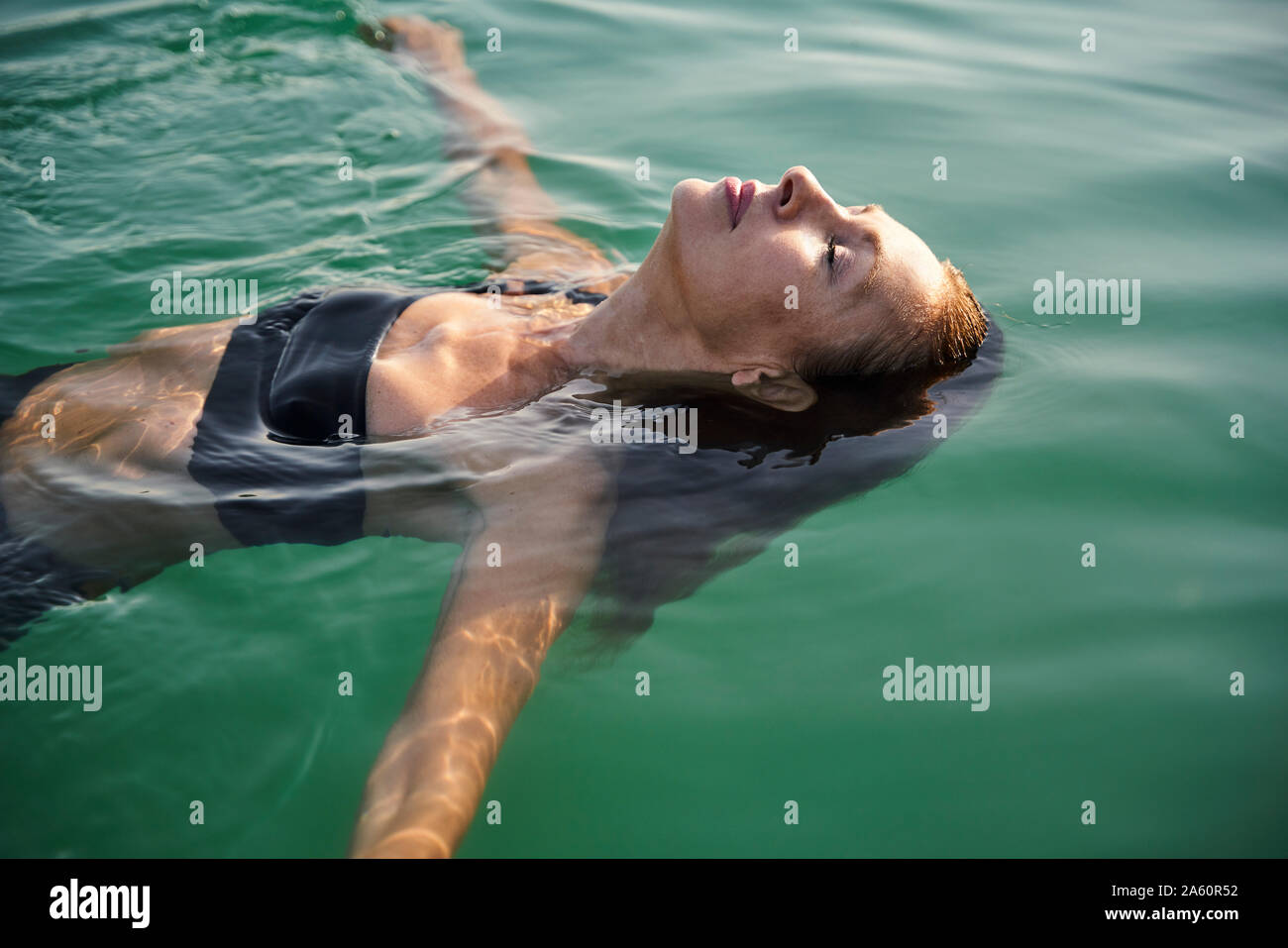 Reife Frau schwimmen in einem See mit geschlossenen Augen Stockfoto