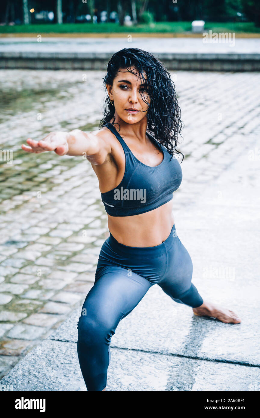 Frau Yoga im Regen, Krieger darstellen Stockfoto