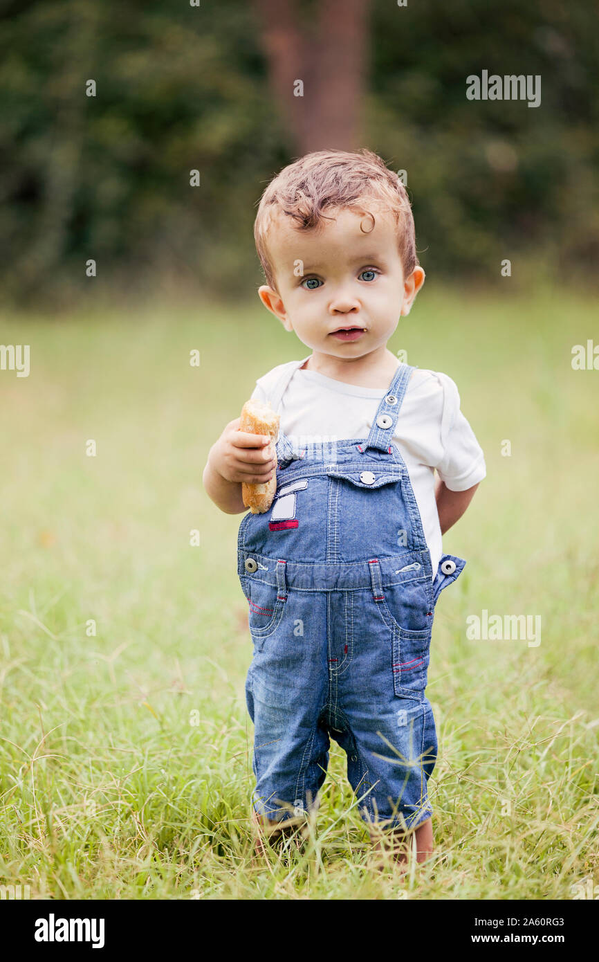 Portrait von kleinen Jungen tragen Jeans Latzhose stehen auf einer Wiese  Stockfotografie - Alamy