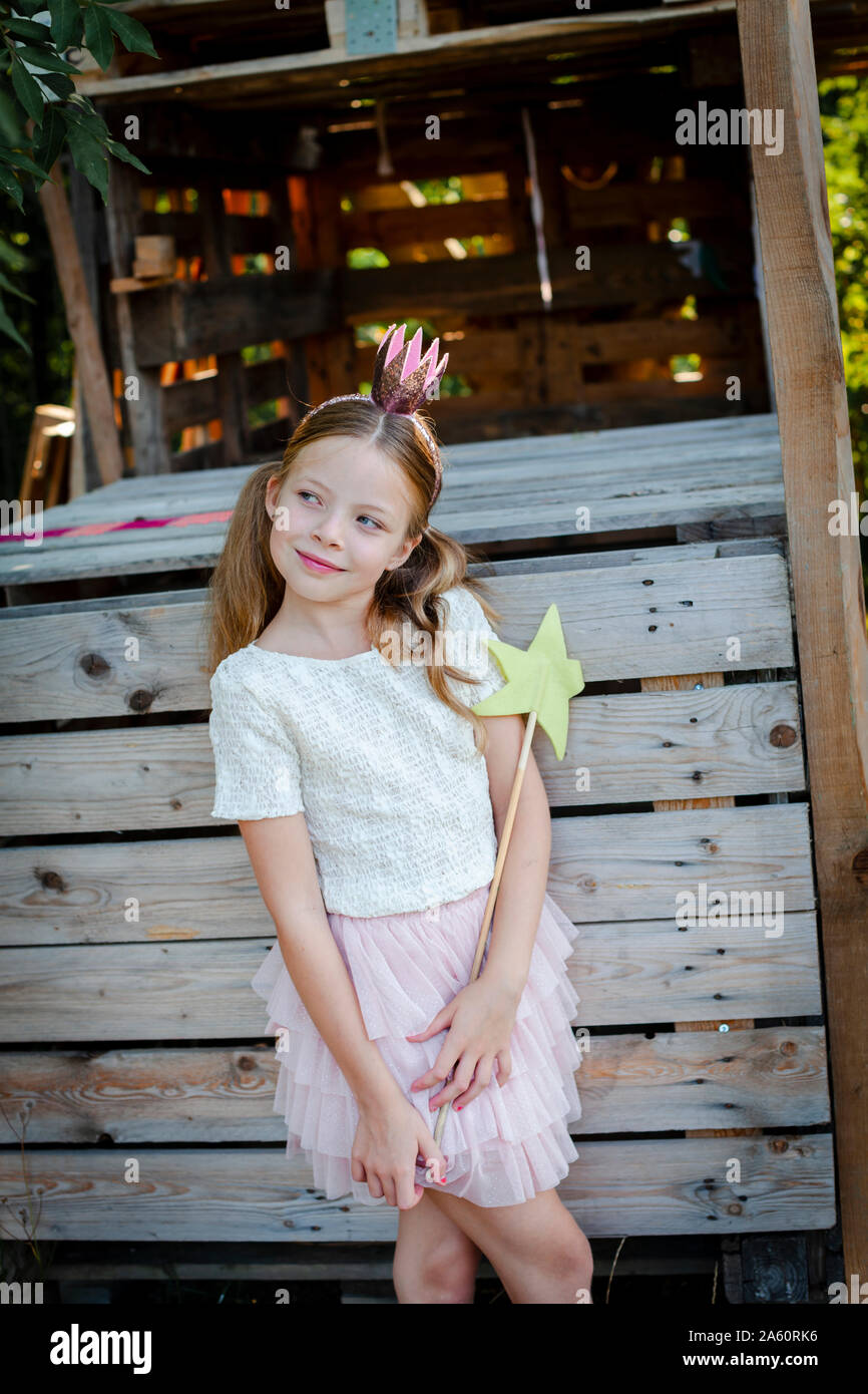 Mädchen gekleidet wie eine Prinzessin mit Krone und Zepter spielen in einem Baumhaus Stockfoto
