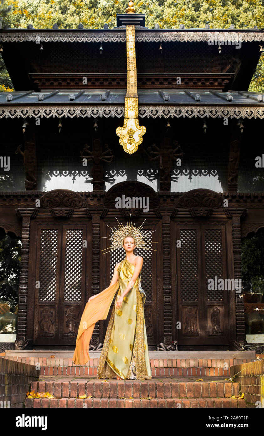 Junge Frau in Kleid und Kopfbedeckung vor einer Pagode Stockfoto