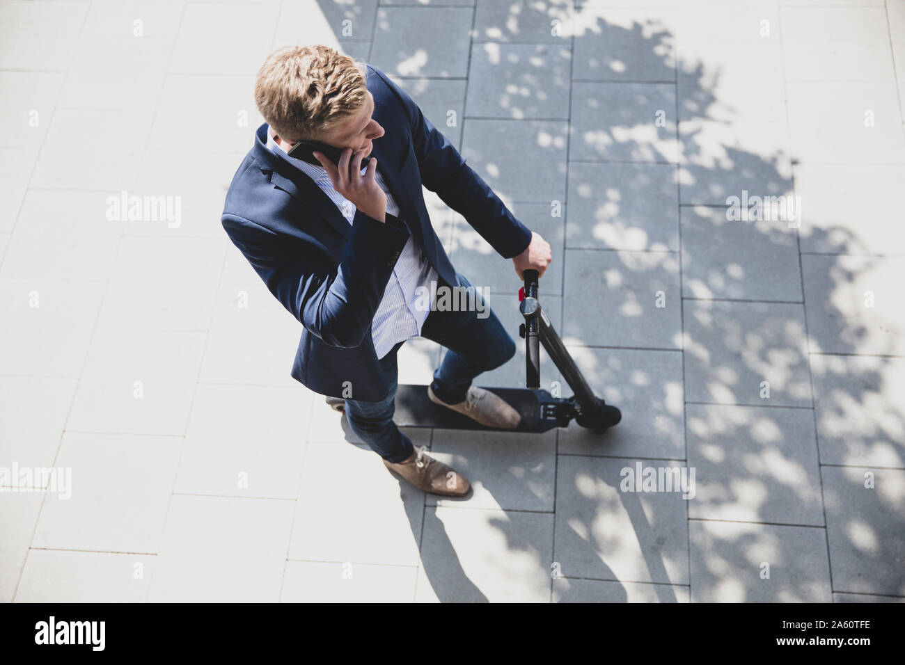 Junger Mann mit e-Scooter, am Telefon zu sprechen in der Stadt Stockfoto