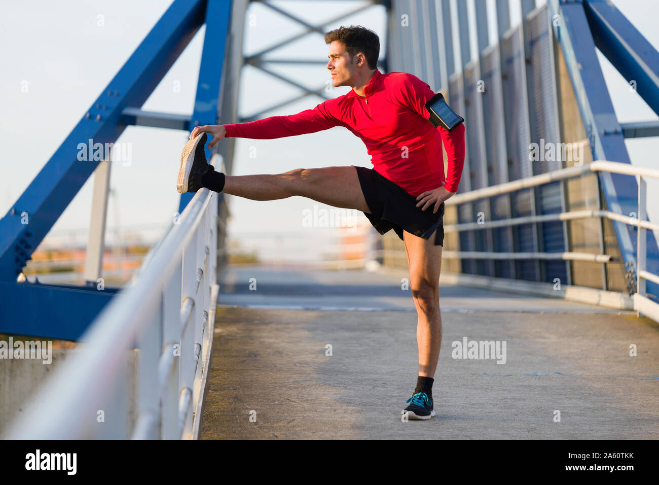 Jogger mit Smartphone im Arm pocket sein Bein strecken Stockfoto