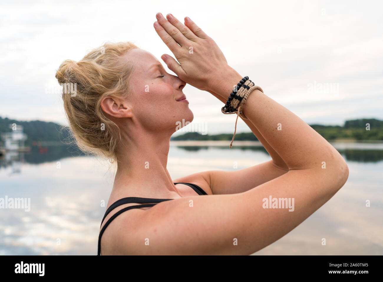 Junge Frau mit gefalteten Händen an einem See Stockfoto