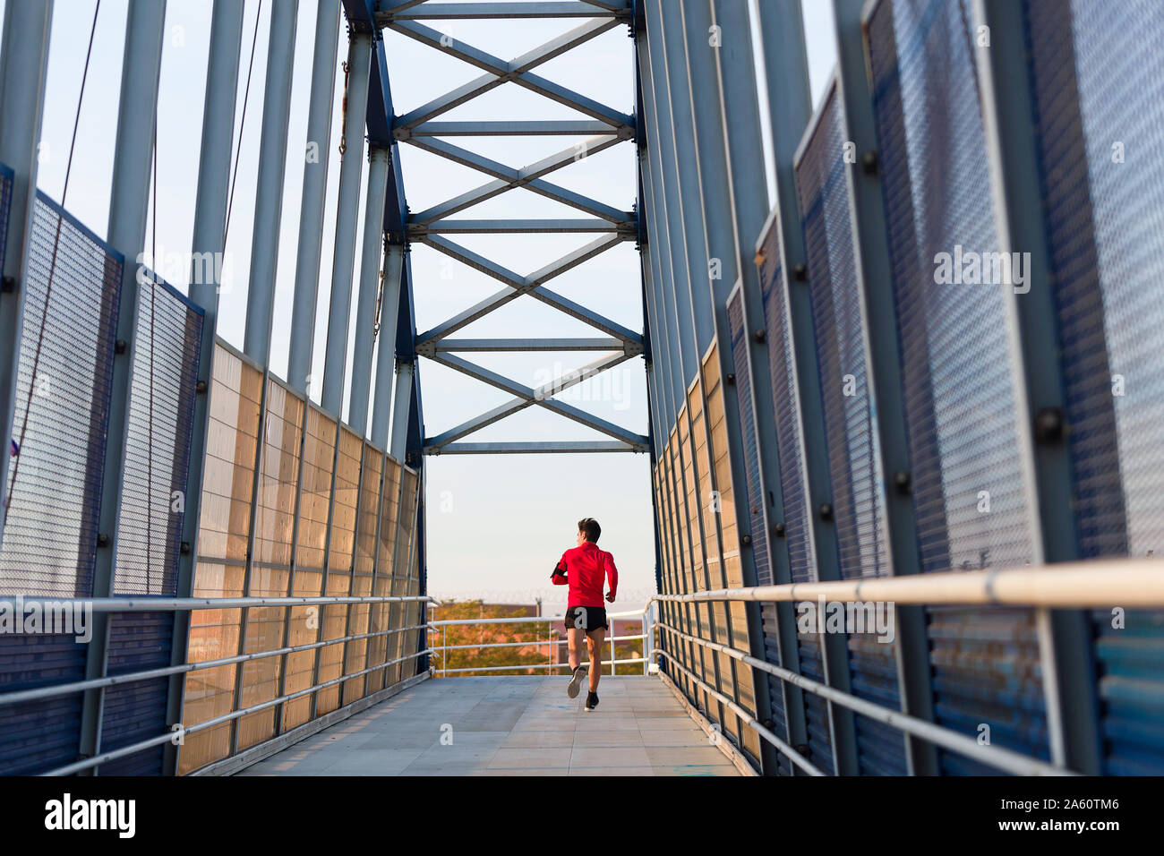 Ansicht der Rückseite ein Jogger mit Smartphone im Arm pocket läuft auf einer Brücke Stockfoto