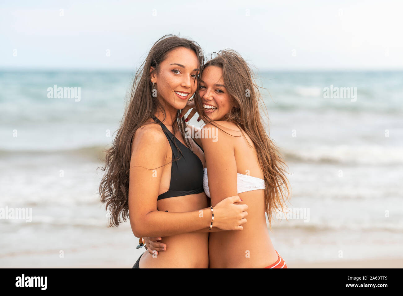 Portraitof zwei Glückliche weibliche Freunde umarmen am Strand Stockfoto