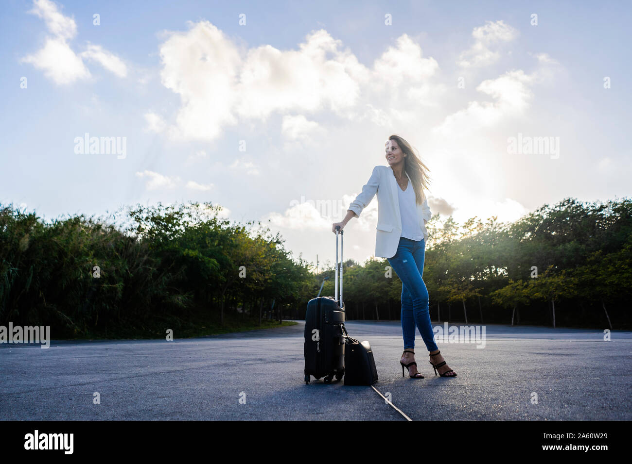 Mit Gepäck steht auf einer abgelegenen Straße Geschäftsfrau Stockfoto