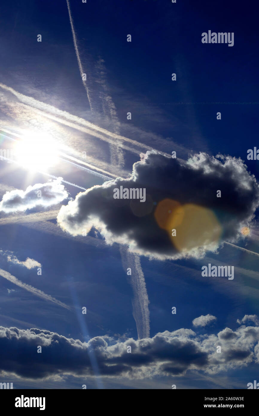 Blauer Himmel mit Wolken, Sonne und Kondensstreifen Stockfoto