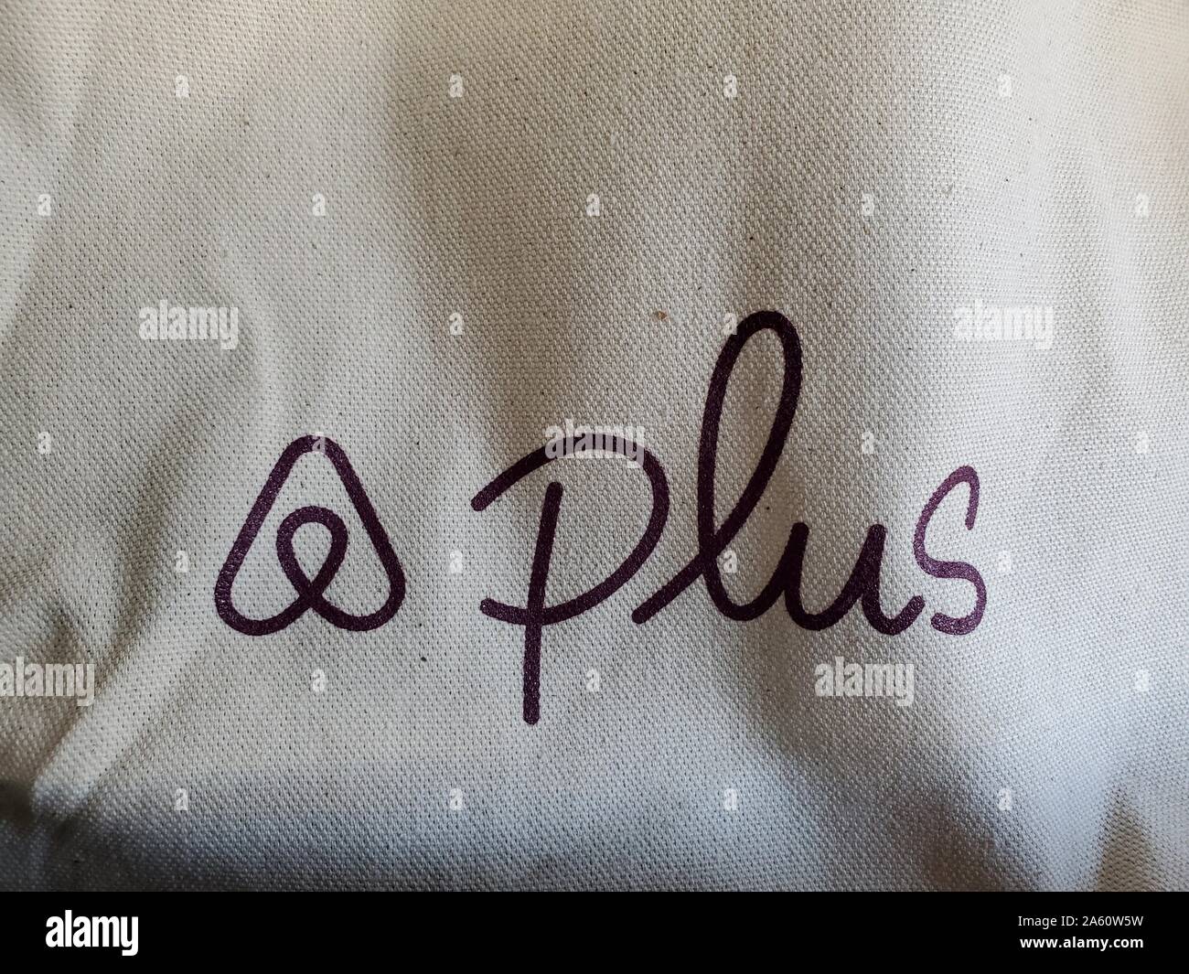 Stilisiertes Logo für Airbnb Plus, ein Service aus der gemeinsamen Nutzung der Economy-Urlaub-Mietfirma Airbnb, der die Vermietung von höhergelegenen Häusern auf einer Burlap Fabric-Oberfläche ermöglicht, San Ramon, Kalifornien, 24. September 2019. () Stockfoto