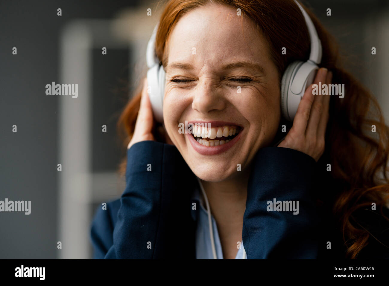 Portrait von lachende Rothaarige geschäftsfrau Musik hören mit weißen Kopfhörer Stockfoto