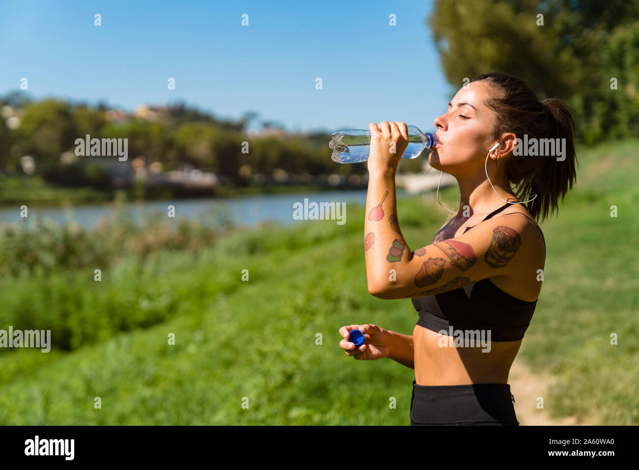 Sportliche junge Frau mit einem kühlen Pause am Flußufer Stockfoto