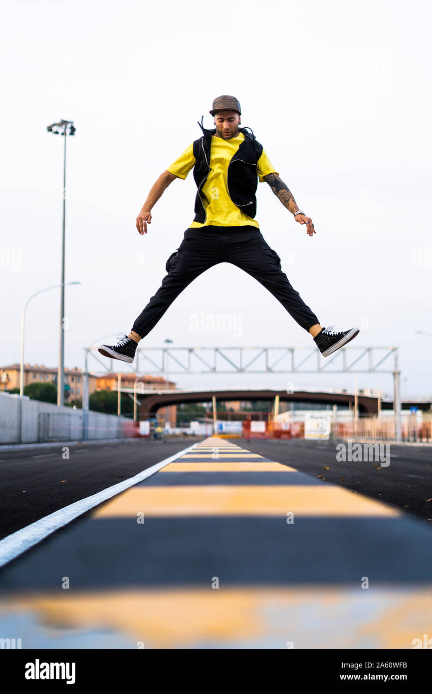 Tätowierte junge Mann springen in die Luft, Stockfoto