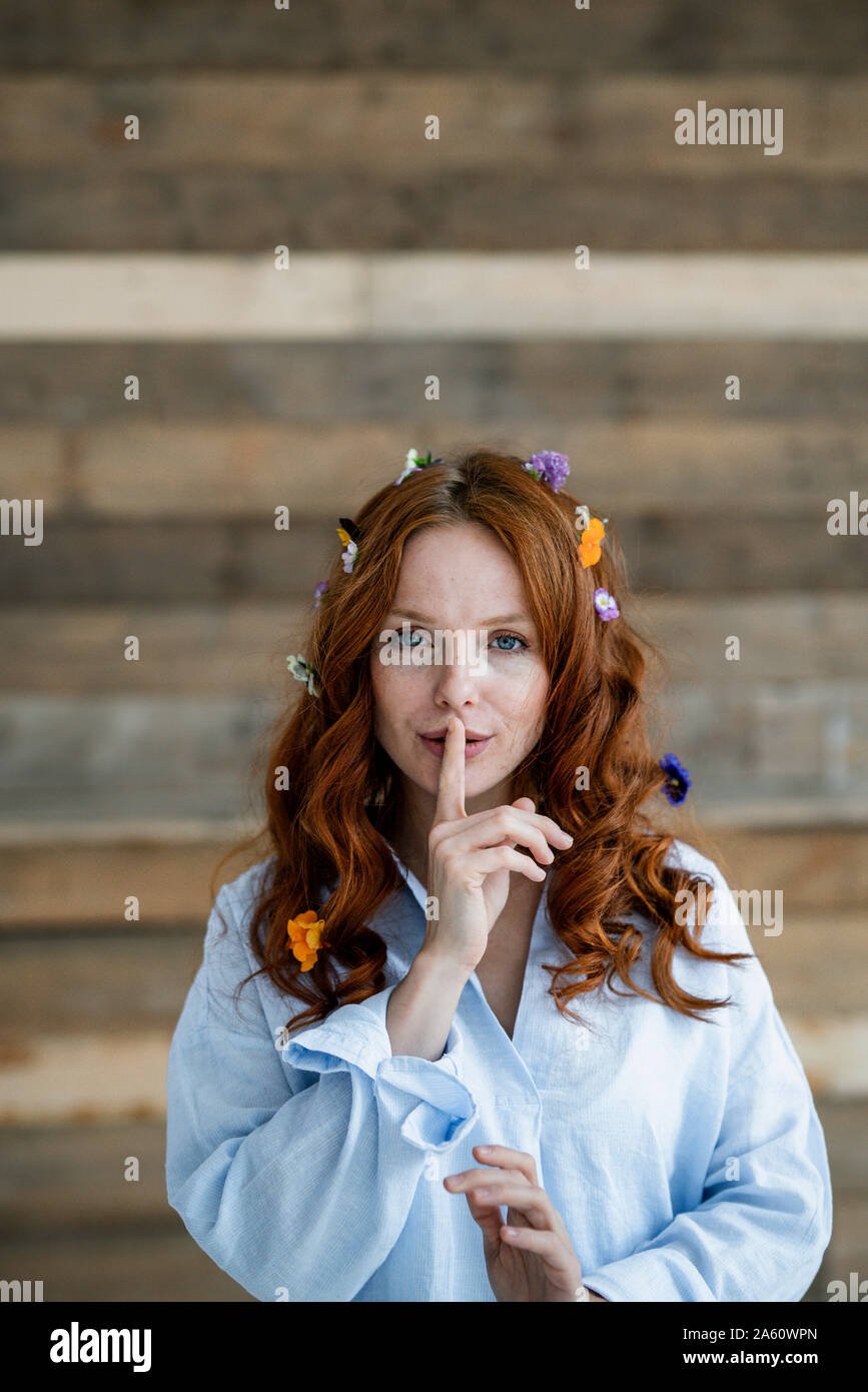 Porträt der rothaarige Frau mit Blüten im Haar und den Finger auf den Mund, Stockfoto