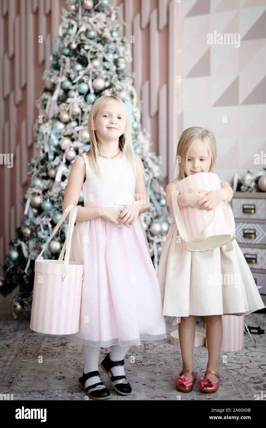 Porträt von zwei glücklichen kleinen Mädchen mit Geschenk Boxen stehen vor der beleuchteten Weihnachtsbaum Stockfoto