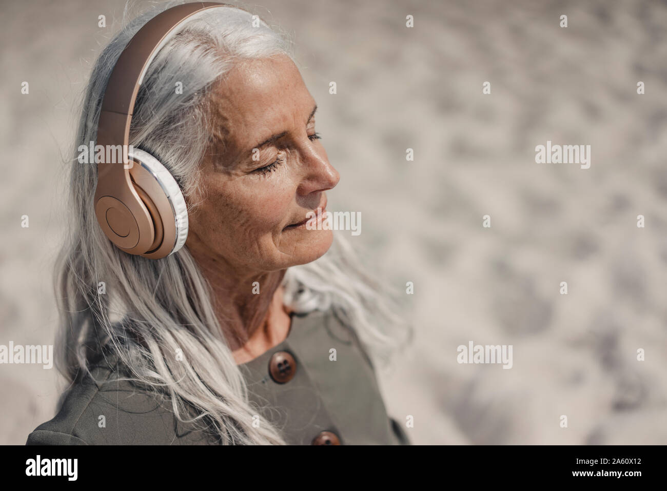 Ältere Frau Musik hören mit Kopfhörern am Strand Stockfoto