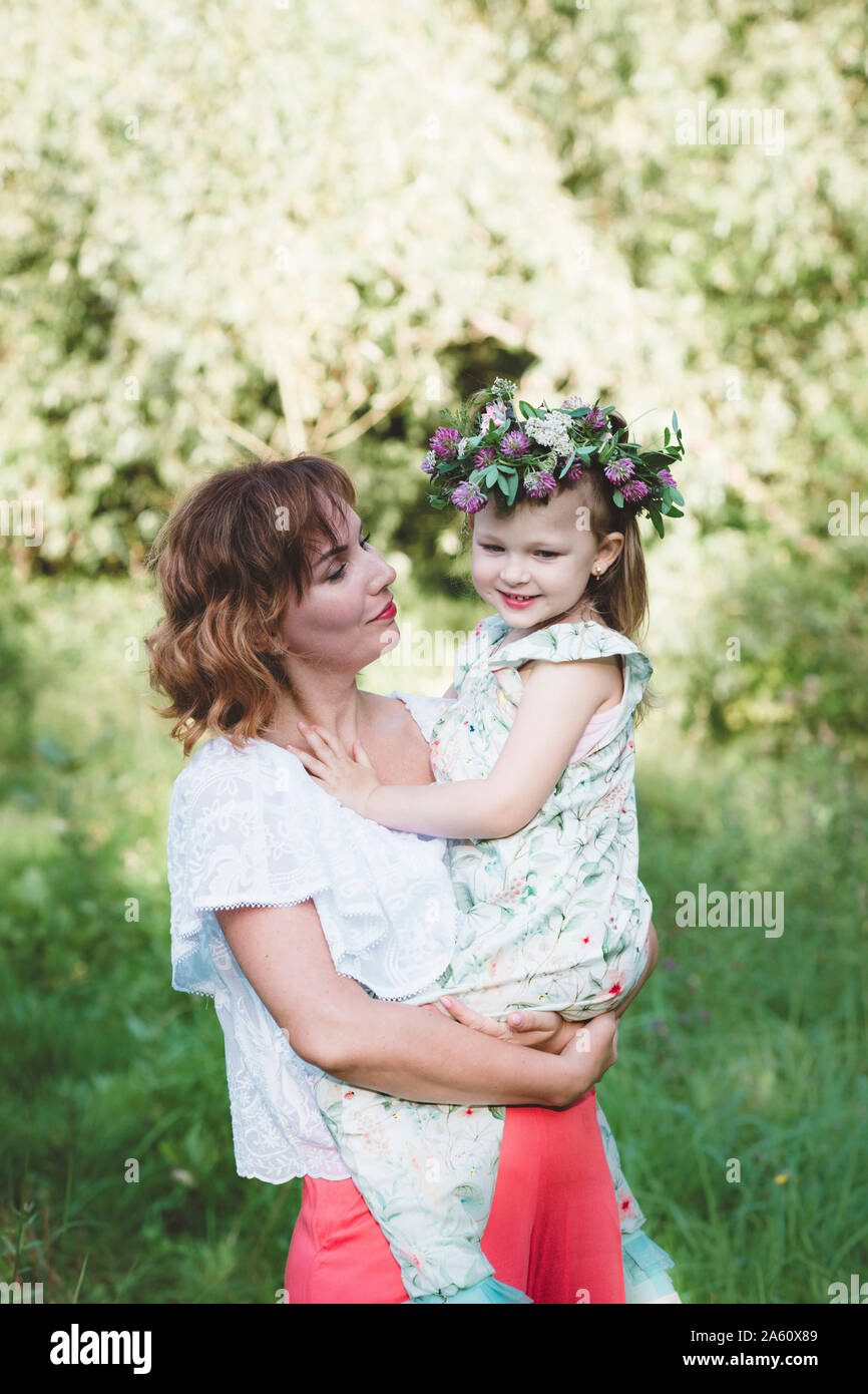 Mutter Holding Tochter mit Blumenkranz Stockfoto